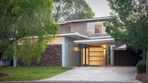 A modern two-story house with a covered garage, a stone wall, and a well-maintained lawn. - Breezy Bay Retreat: Family Haven near Town & Beach (Dunsborough)