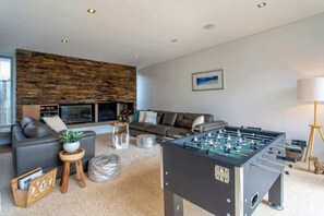 A modern living room with a foosball table, a sofa, a coffee table, and a fireplace. - Breezy Bay Retreat: Family Haven near Town & Beach (Dunsborough)