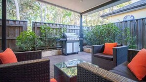 An outdoor patio with wicker furniture, a grill, and a wooden fence. - Breezy Bay Retreat: Family Haven near Town & Beach (Dunsborough)