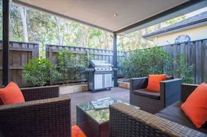 An outdoor patio with wicker furniture, a grill, and a wooden fence. - Breezy Bay Retreat: Family Haven near Town & Beach (Dunsborough)