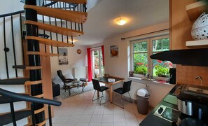 A compact kitchen with a dining area, a staircase, and a view of greenery outside. - Vacation apartment SE-SCH - Holiday apartment Schernau (Sellin)
