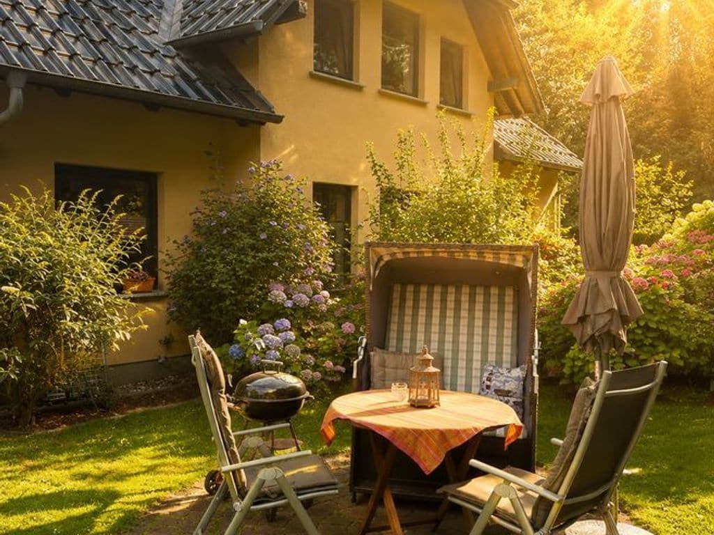 A patio with a table and chairs, a grill, and a covered seating area with a striped cushion.