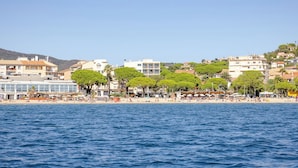 A coastal town with a beach, buildings, and trees.