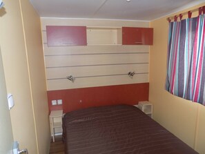 A room with a bed, a wardrobe, a mirror, and a window with curtains.
