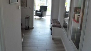 En hall med en bänk, en stol och en dörr med en spegel.