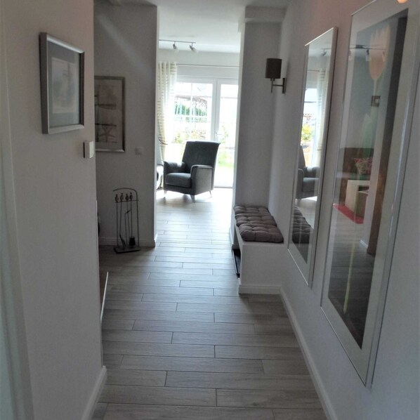 A hallway with a bench, a chair, and a door with a mirror.