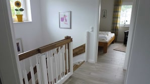 En hall med ett träräcke, en säng med en träram och ett fönster med en solros.