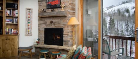 Ample seating by the fireplace with gorgeous views visible through the sliding door—perfect for cozy gatherings.