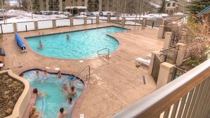 A swimming pool with multiple lanes and a separate hot tub area, surrounded by a fenced patio with lounge chairs. - Best Location-True Hike In/Out TH w/Slope Views-Heated Pool-HotTub-Gym-W/D in Unit-Fireplace-Updated (Steamboat Springs)