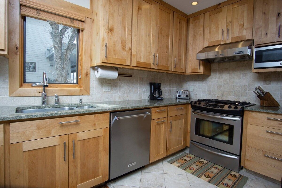 A kitchen with wooden cabinets, stainless steel appliances, a dishwasher, a stove, and a microwave.
