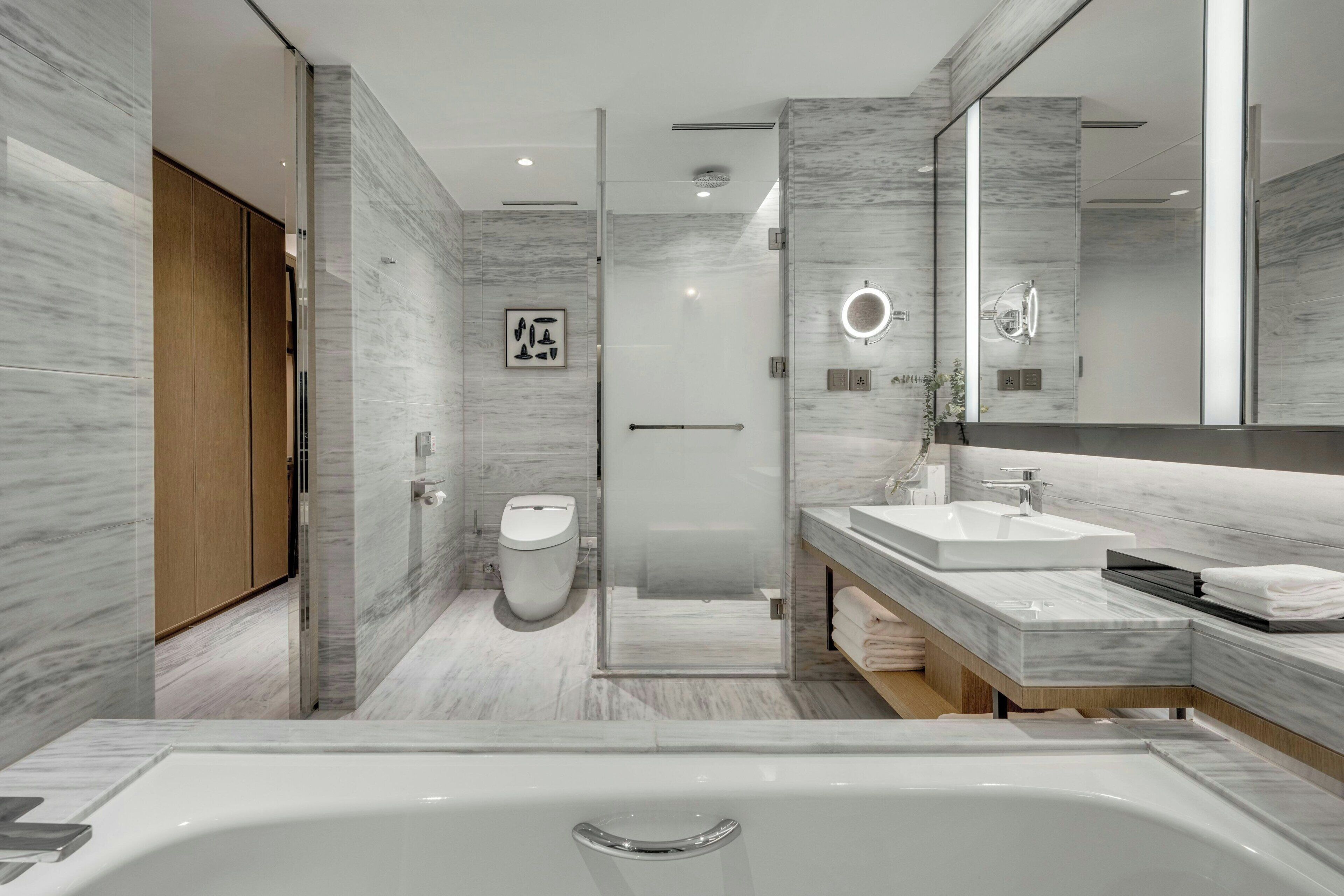A modern bathroom with a large bathtub, a toilet, and a shower area.