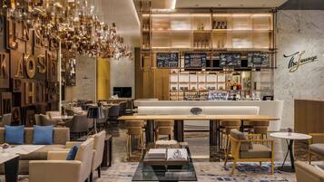 A modern lounge area with seating, a bar, and a coffee station.