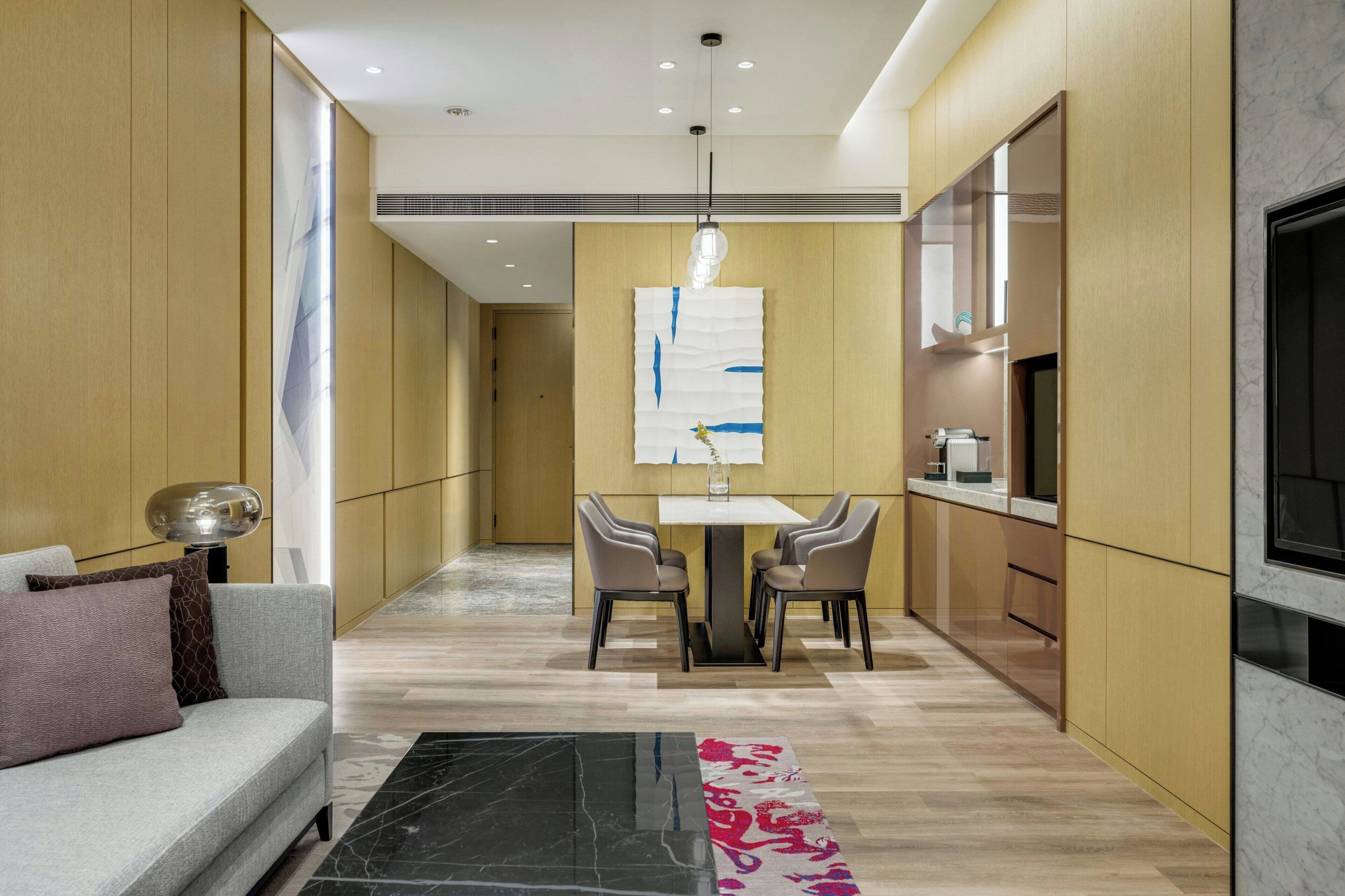 A modern interior with a sofa, dining table, chairs, and a kitchen area.