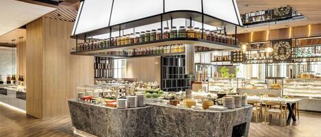A modern hotel lobby with a marble reception desk, a glass display case with food items, and a high ceiling with wooden paneling.