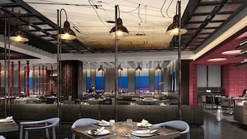 A modern restaurant with high ceilings, pendant lighting, and a view of the cityscape through large windows.