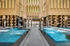 Un espace piscine comprenant deux piscines, une allée centrale et une vue sur l’intérieur du bâtiment.