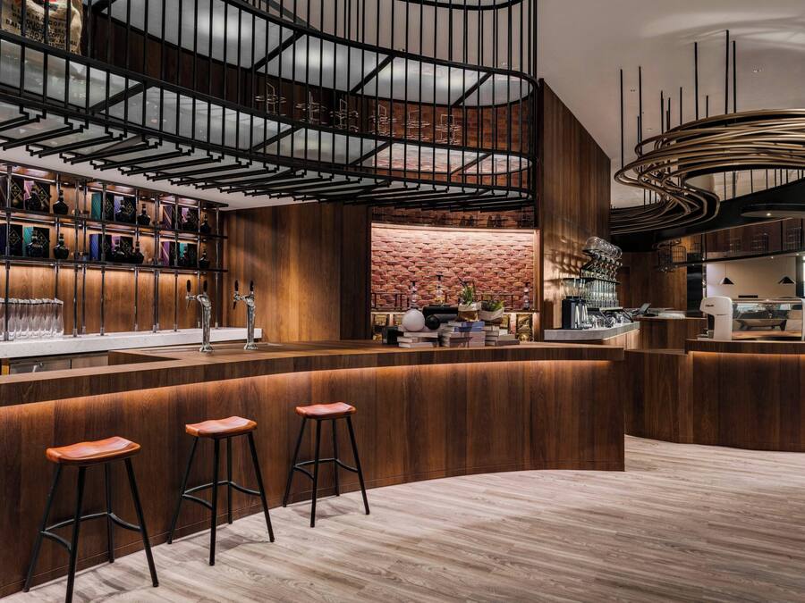 A modern bar area with wooden accents, a brick wall, and a curved ceiling design.