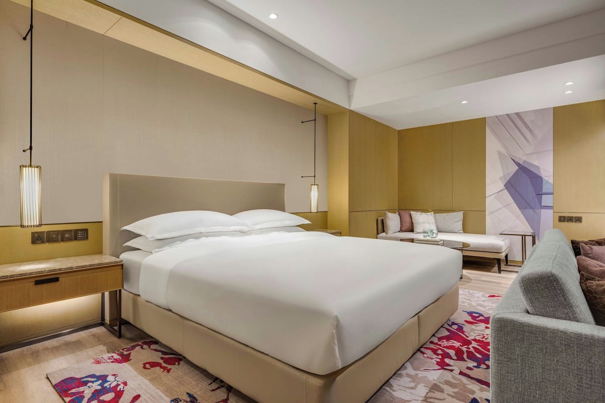 Una habitación de hotel con una cama grande, un escritorio, una silla y un sofá.