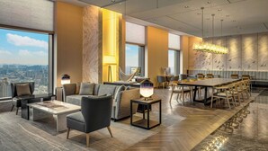 Un moderno vestíbulo de hotel con una amplia mesa de comedor, asientos cómodos y vistas a la ciudad.