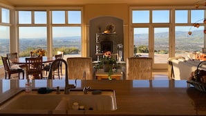 Amplia sala de estar con un gran ventanal con vistas panorámicas, chimenea y comedor con mobiliario de madera.