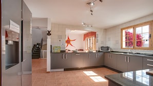 Una cocina moderna con armarios grises, un refrigerador de acero inoxidable y un ventanal con vistas a flores rosadas.