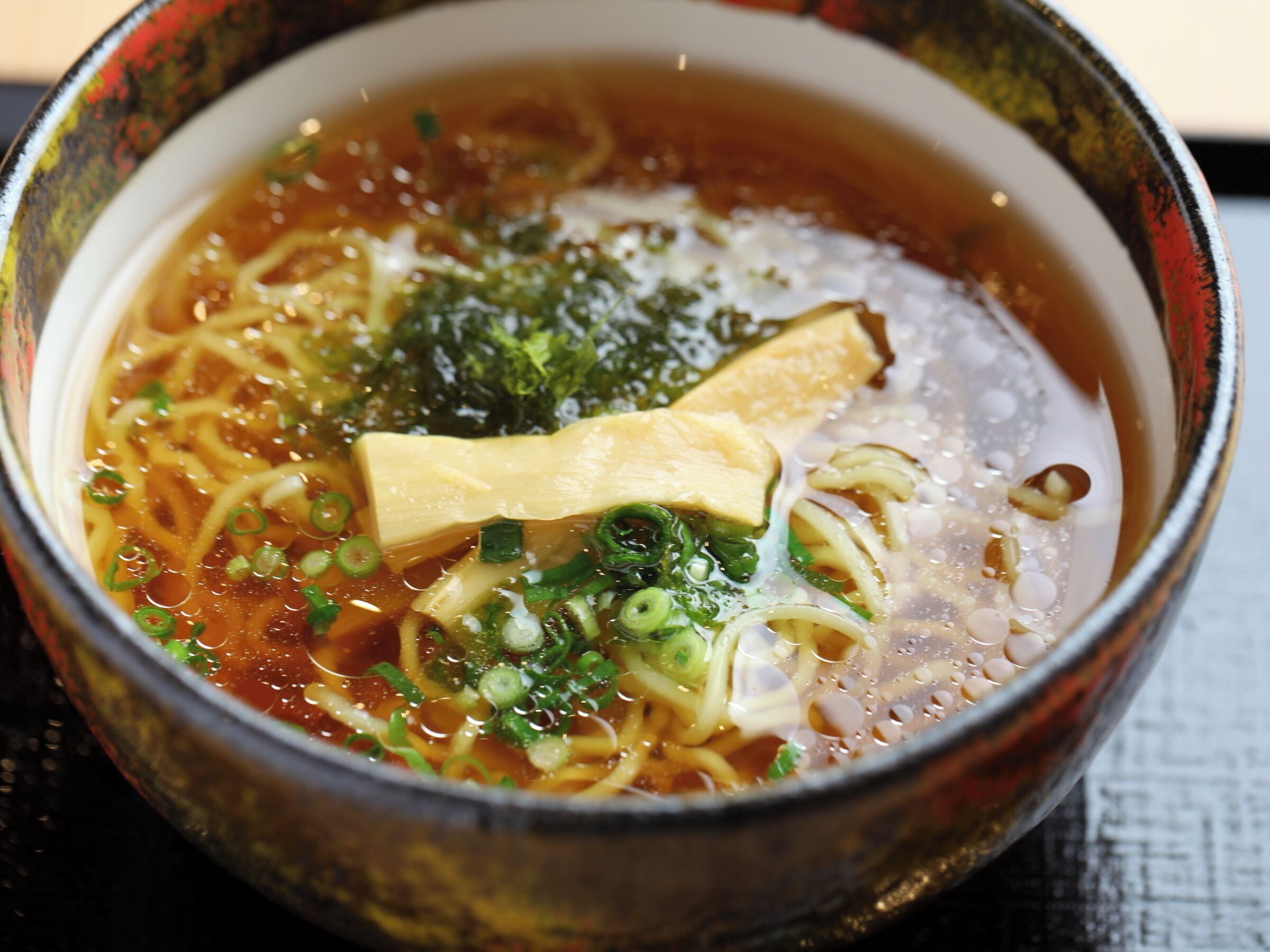 A bowl of ramen with noodles, tofu, and green onions in a broth.