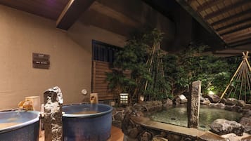 Ein traditionelles japanisches Onsen mit zwei großen Steingrößen, einer kleinen Holzstruktur und einem Steingarten.
