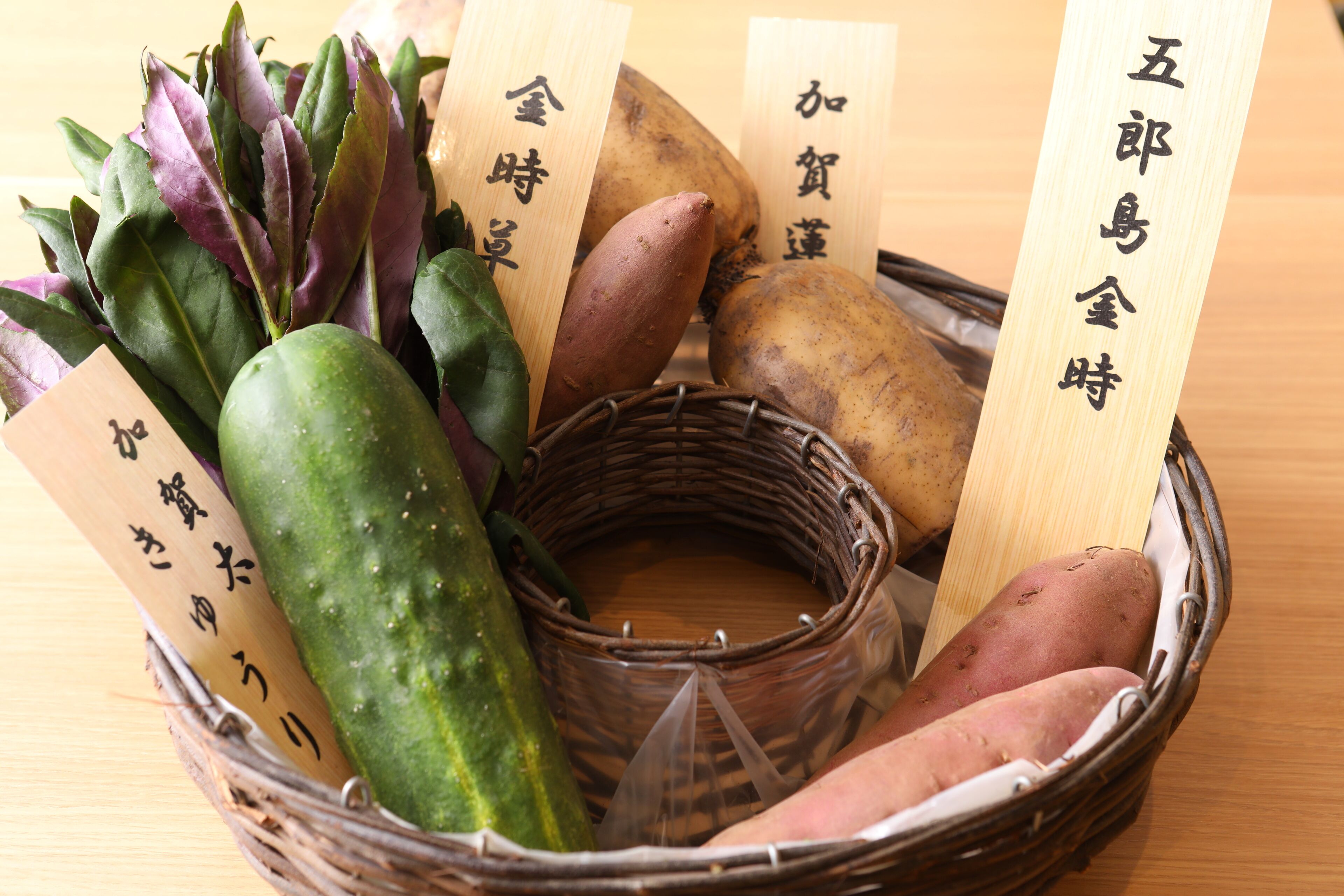 A basket containing various vegetables and wooden tags with text.