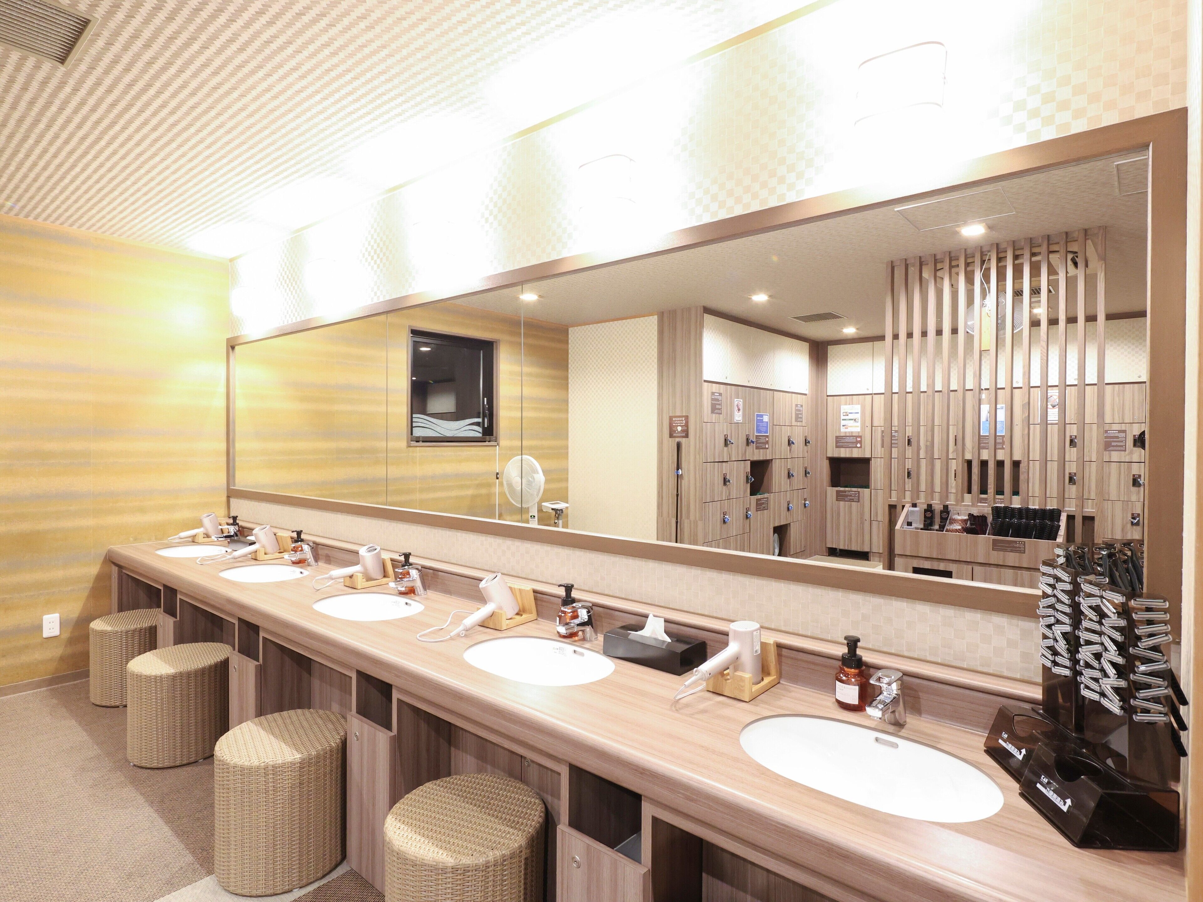 Un baño de hotel con tres lavamanos, un espejo grande y un perchero para toallas.