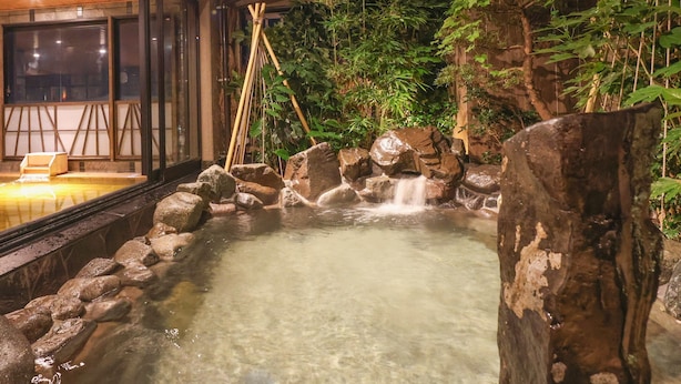 A hot spring area with a wooden deck, rocks, and bamboo. - Onyado Nono Kanazawa Natural Hot Spring (Kanazawa)