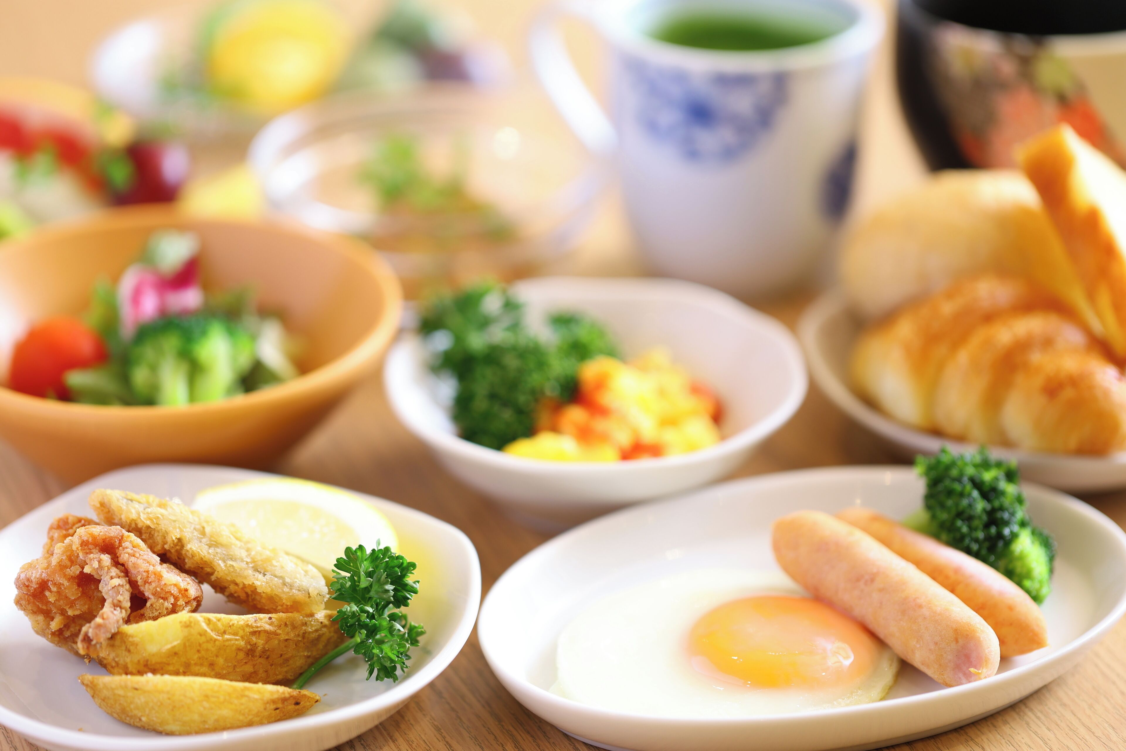 Une variété de plats, notamment du poulet frit, des œufs et des légumes, disposés sur une table en bois.