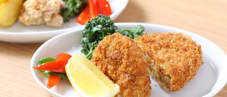 A plate with breaded chicken cutlets, lemon wedge, and mixed vegetables.
