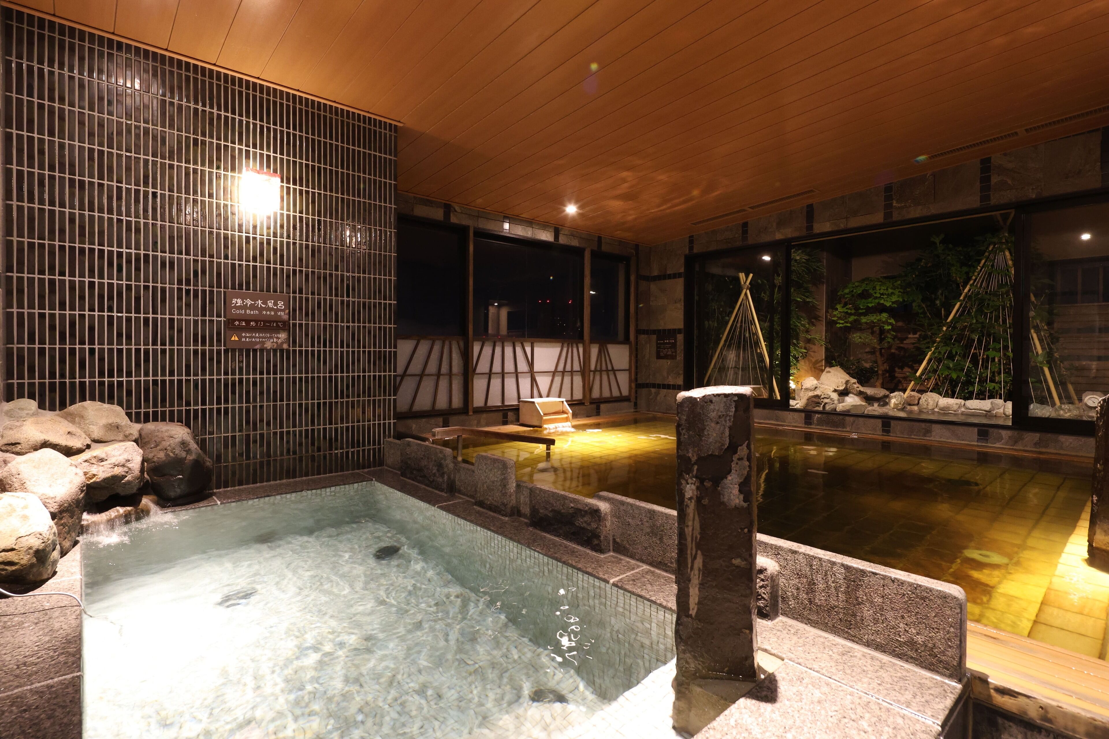 Un’area con sorgenti termali, una piccola piscina, panche in legno e un muro rivestito di piastrelle.