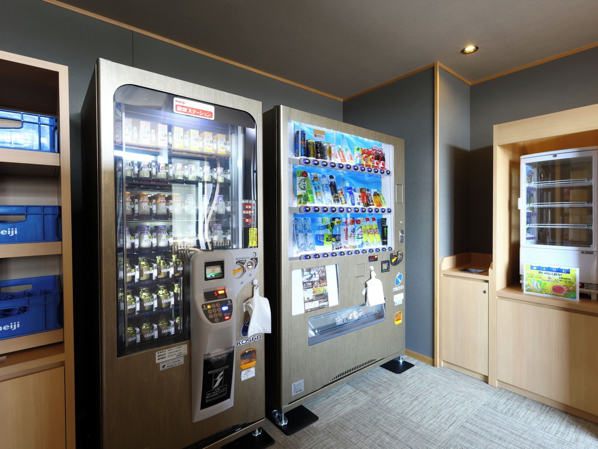 Two vending machines in a room with wooden cabinets and a gray carpet.