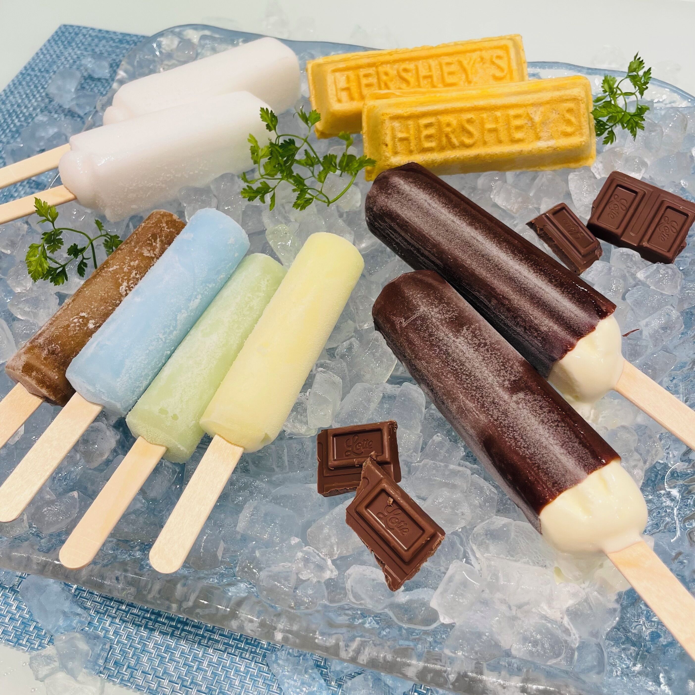 A variety of ice cream bars and chocolate pieces on a bed of ice.