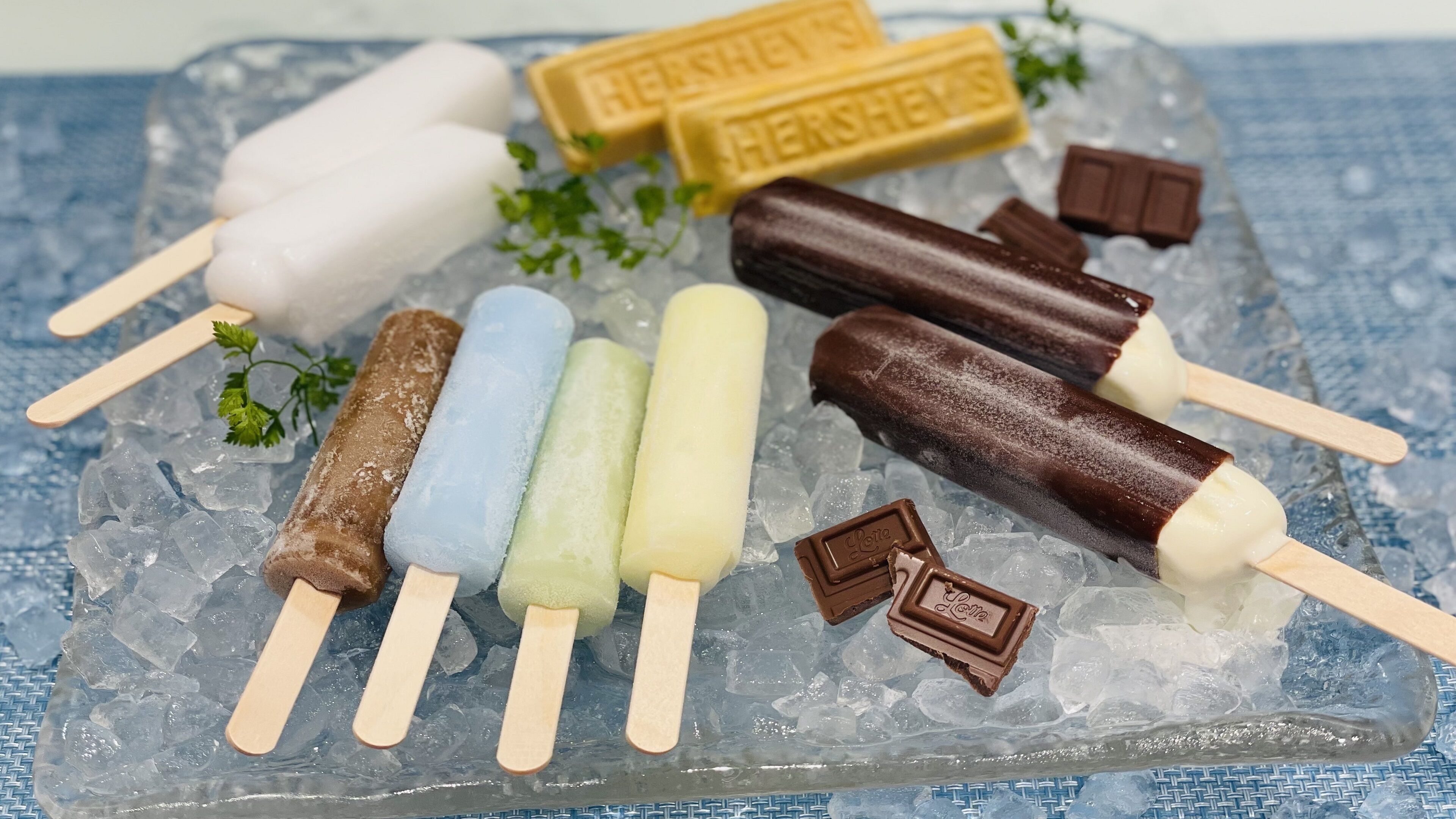 A selection of ice cream bars and chocolate pieces on a bed of ice.