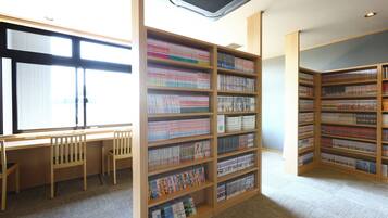 A library with wooden bookshelves and a reading area with chairs.