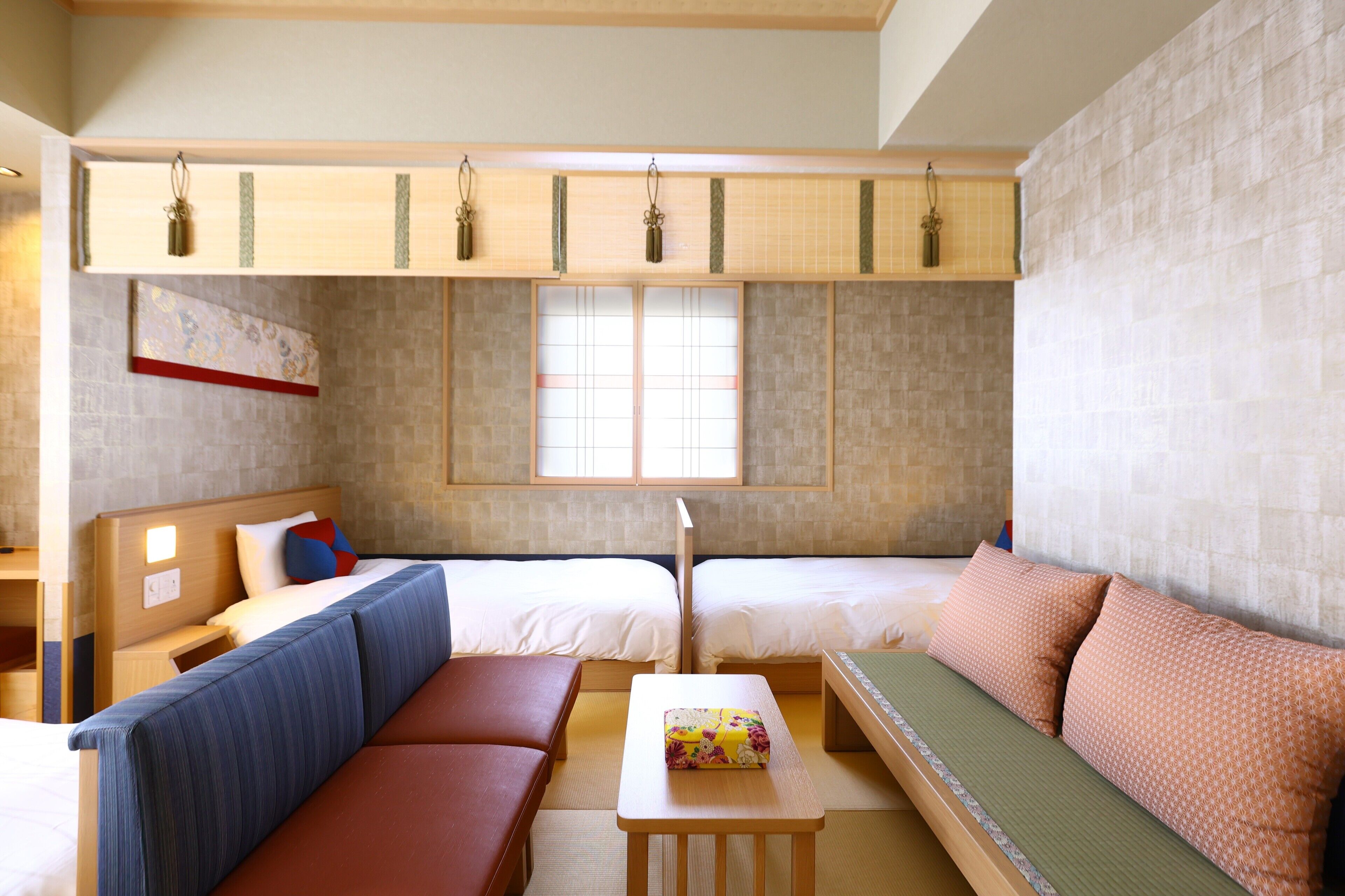 A traditional Japanese-style room with tatami flooring, a low wooden bed, a cushioned bench, and a small table with a floral-patterned box.