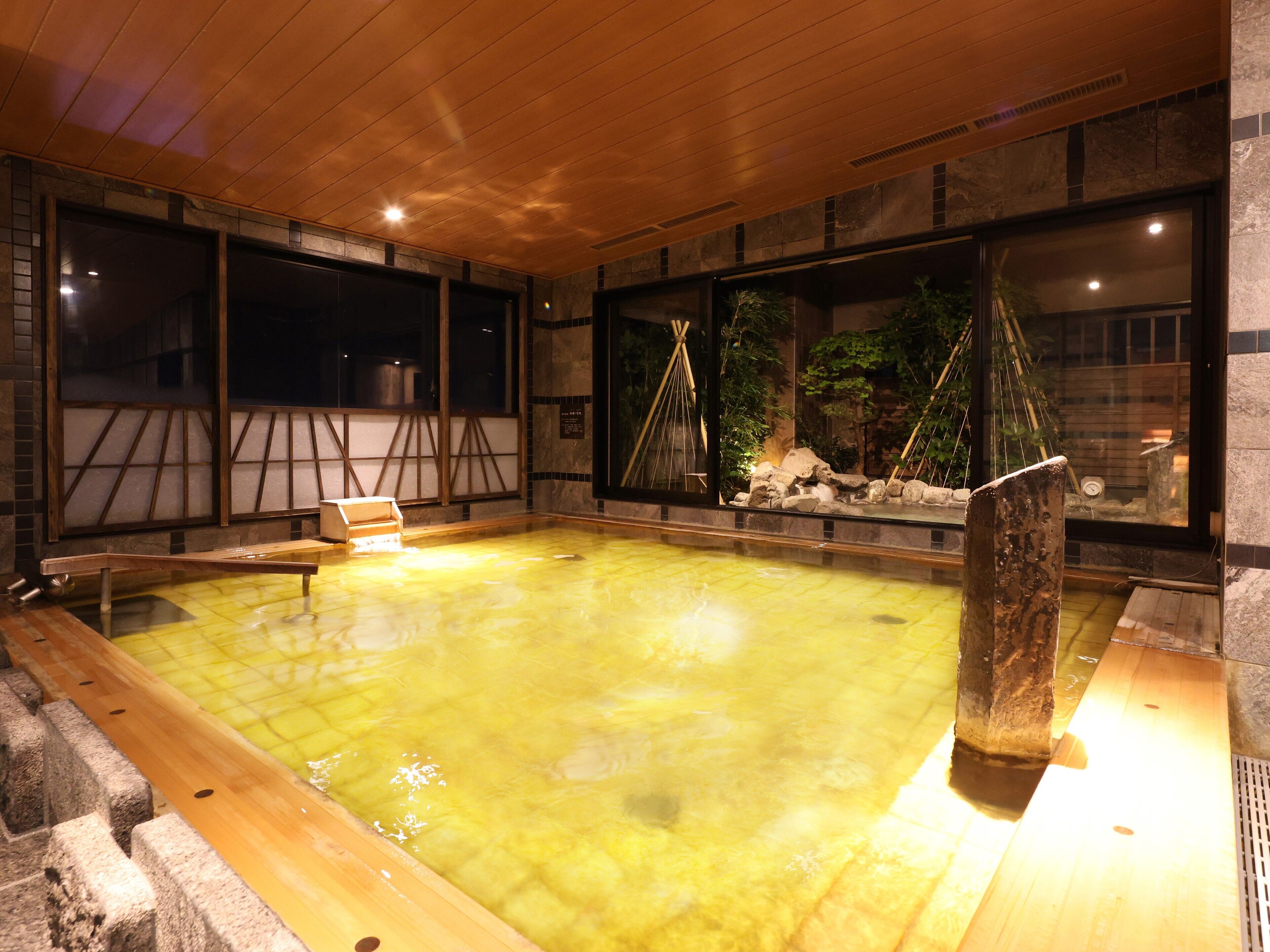 A traditional Japanese onsen with a wooden deck, stone walls, and a view of the surrounding nature.