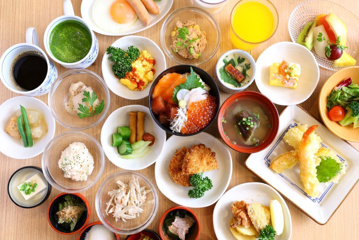 A variety of dishes arranged on a wooden table, including sushi, sashimi, and other Japanese cuisine.