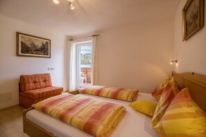 Une chambre à coucher avec un lit, deux oreillers, un canapé, une fenêtre et un tableau au mur.