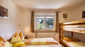 Een kamer met twee bedden, een raam met uitzicht op een bos en een radiator.