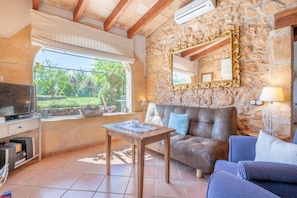 A cozy living area with a stone wall, a large mirror, a sofa, and a television.