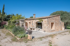 A stone building with a patio, outdoor seating, and a garden.