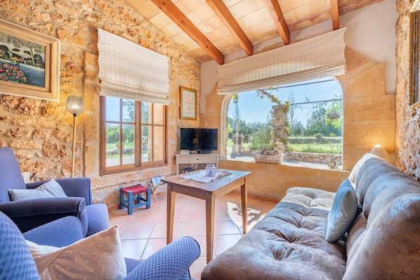 A stone-walled room with a TV, sofas, and a small table.