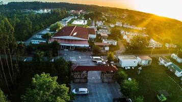 An aerial view of a residential area with houses, a large building with a red roof, and a parking lot.