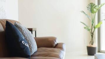 A brown leather sofa with patterned cushions, a small table, and a potted plant in a corner.