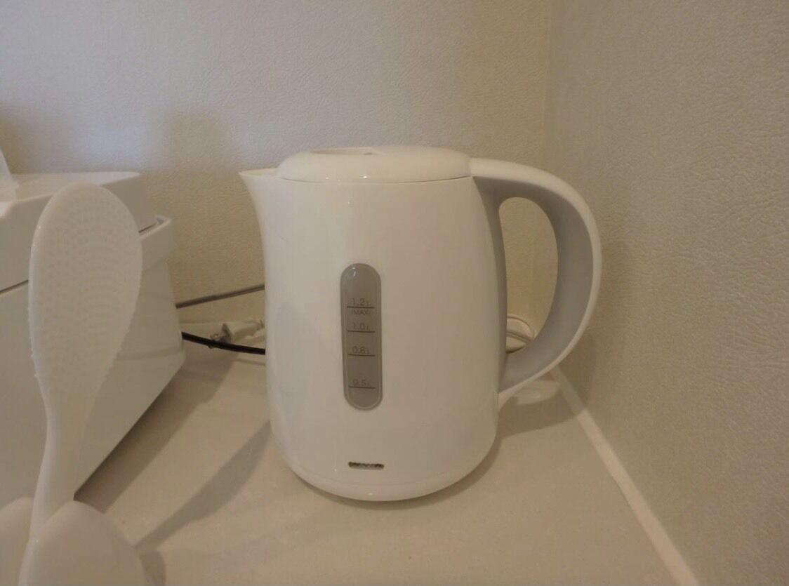 A white electric kettle with a control panel on a white countertop.