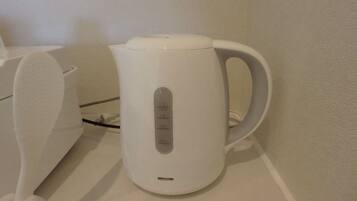 A white electric kettle with a control panel on a white countertop.