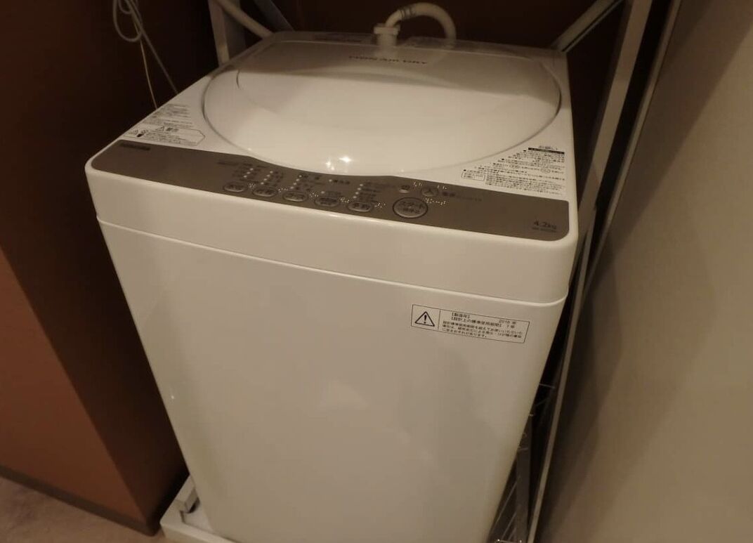 A front view of a white washing machine with a control panel and a safety warning label.